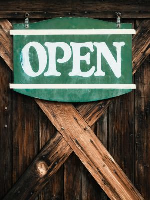 A rustic green 'OPEN' sign on a wooden door in Harmony, California.