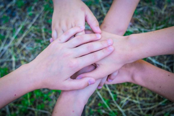 Close-up of diverse hands stacked together as a symbol of unity and teamwork.