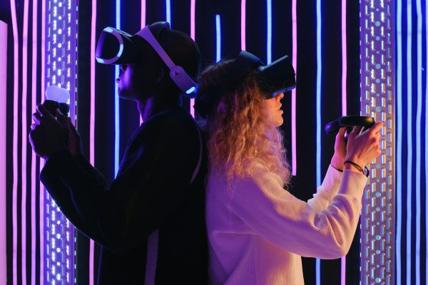 Two adults engaged in virtual reality gaming with VR headsets in a vibrant, neon-lit environment.