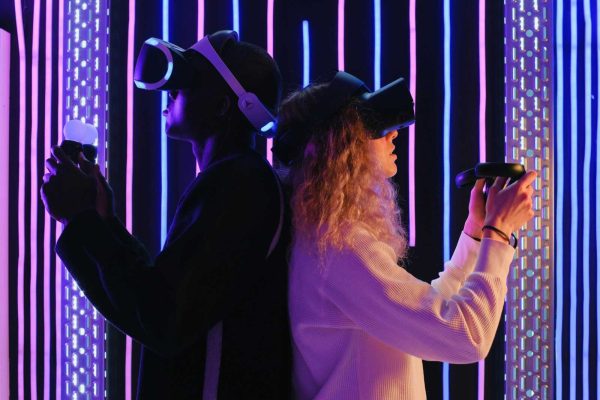 Two adults engaged in virtual reality gaming with VR headsets in a vibrant, neon-lit environment.