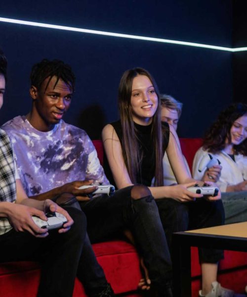 Diverse group of young adults enjoying video games indoors, smiling and having fun.